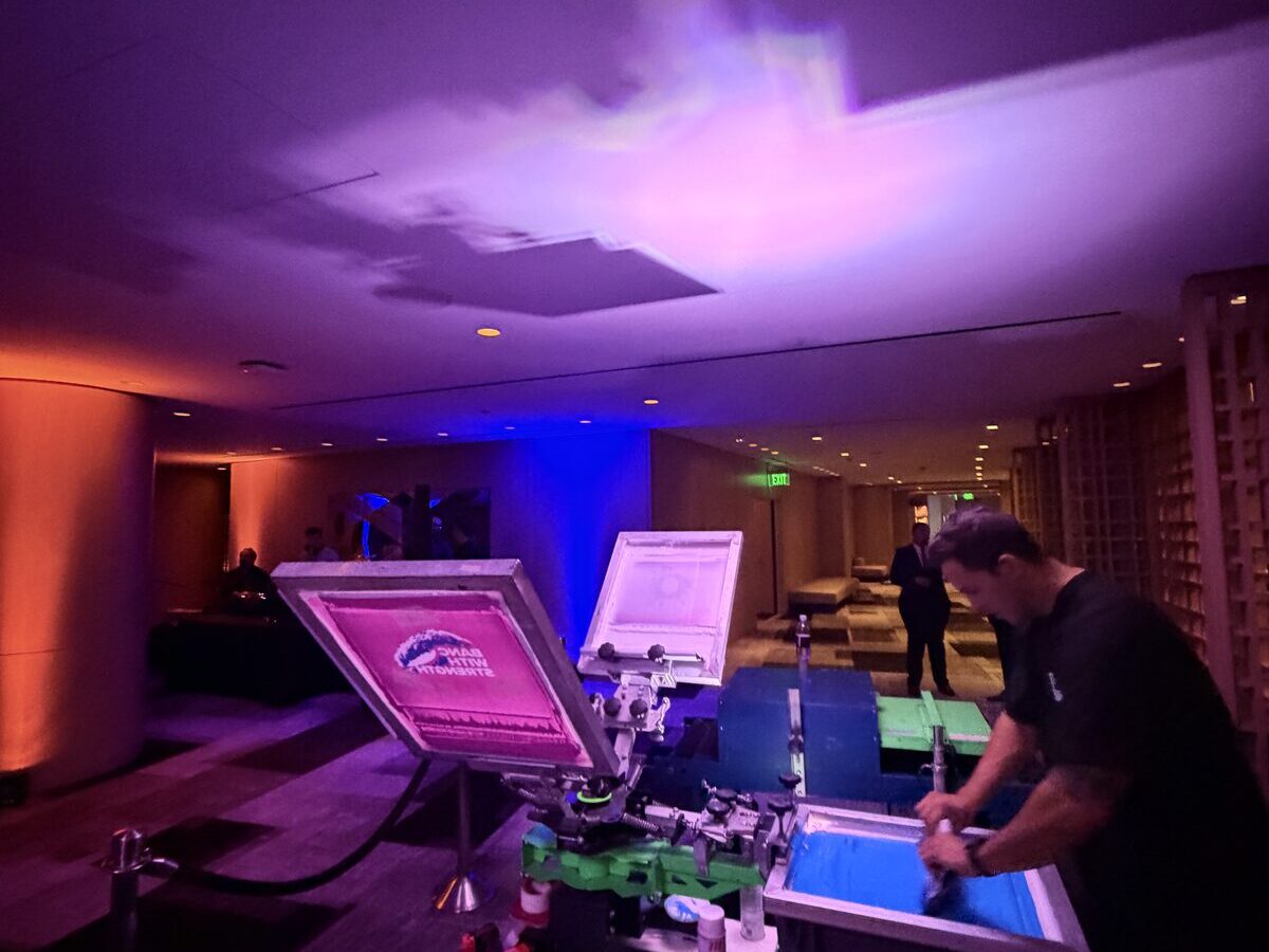 Print station running in a violet-lit hotel corridor during a corporate reception